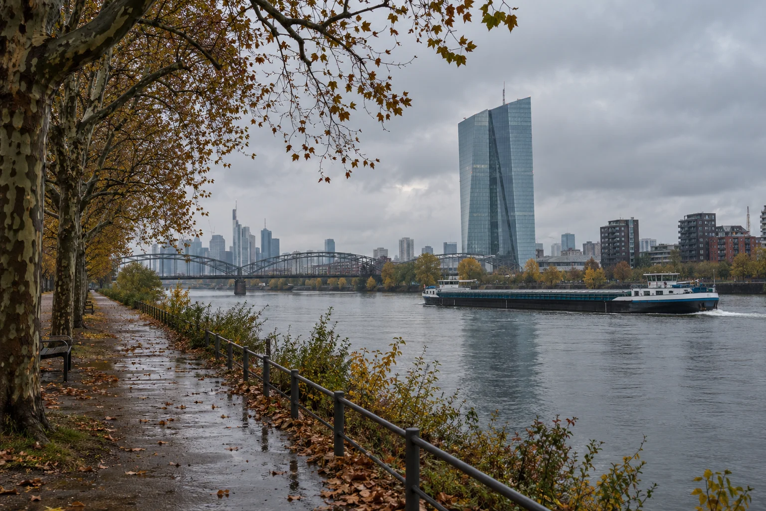 The European Central Bank tower in Frankfurt seen across the river Main under a grey autumn sky.